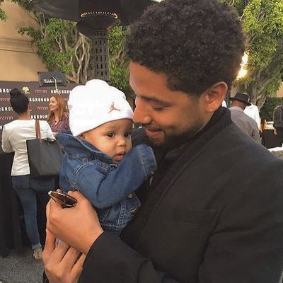 Jussie is holding Hunter close to him as he is in a black suit and Hunter in a denim jacket with white jordan cap.